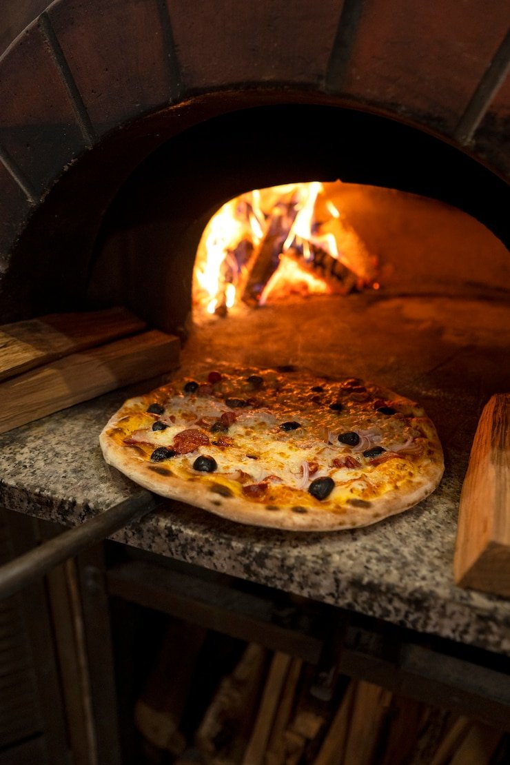 Pizza sendo preparada em forno a lenha